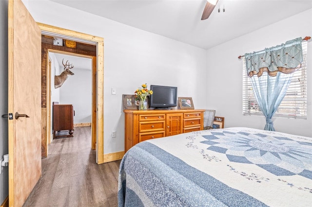 bedroom with ceiling fan, wood finished floors, and baseboards