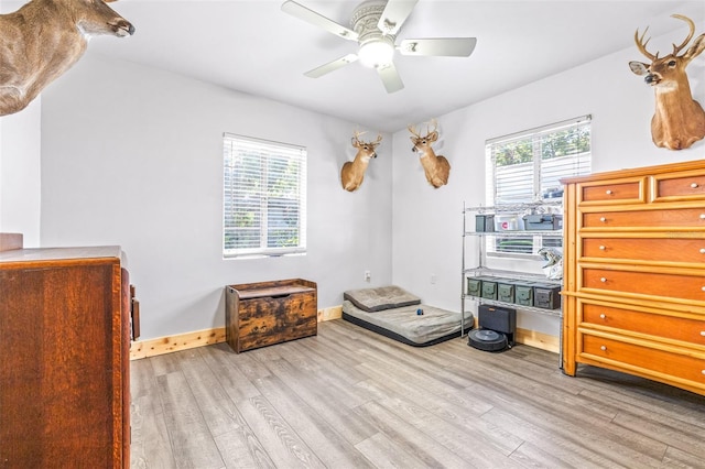 bedroom with multiple windows, light wood-type flooring, and baseboards