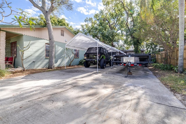 view of parking with a carport, fence, and driveway