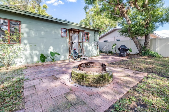 back of house featuring fence, a fire pit, and a patio