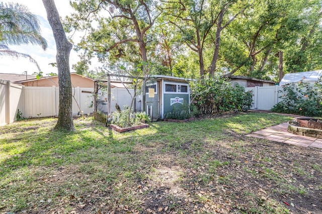 view of yard featuring an outbuilding, a fenced backyard, and a vegetable garden