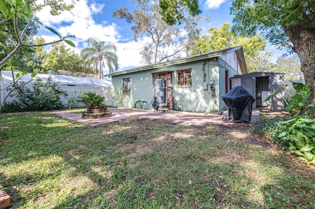 rear view of property featuring a patio area, a yard, an outdoor structure, and fence