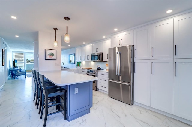 kitchen with marble finish floor, appliances with stainless steel finishes, a breakfast bar, and light countertops