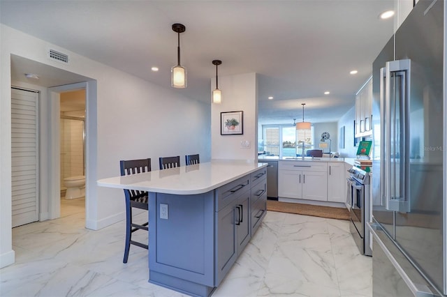 kitchen with marble finish floor, a kitchen bar, appliances with stainless steel finishes, and light countertops