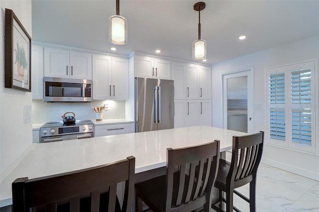 kitchen with appliances with stainless steel finishes, a breakfast bar, marble finish floor, light countertops, and recessed lighting