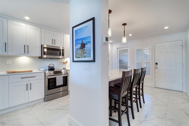 kitchen with appliances with stainless steel finishes, a breakfast bar, marble finish floor, and recessed lighting