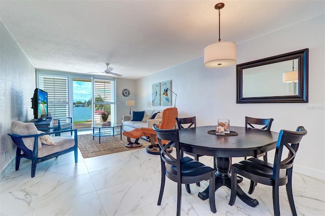 dining area featuring marble finish floor, ceiling fan, and baseboards