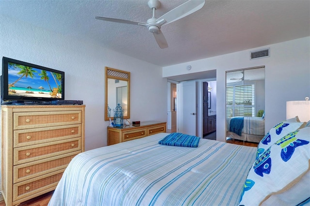 bedroom featuring a textured ceiling, wood finished floors, visible vents, and a ceiling fan