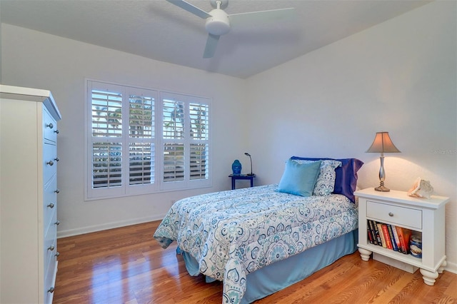 bedroom with a ceiling fan, baseboards, and wood finished floors