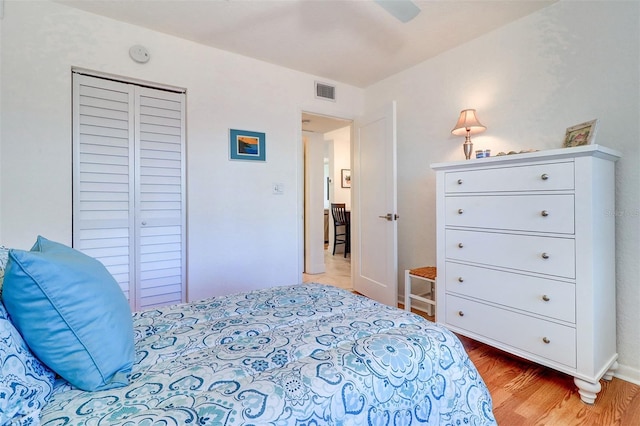 bedroom with a closet, visible vents, ceiling fan, and wood finished floors