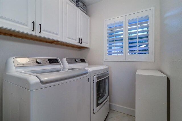 laundry room featuring marble finish floor, baseboards, cabinet space, and independent washer and dryer