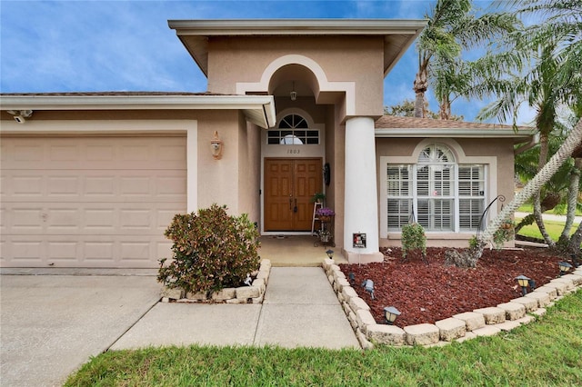 property entrance with a garage and stucco siding