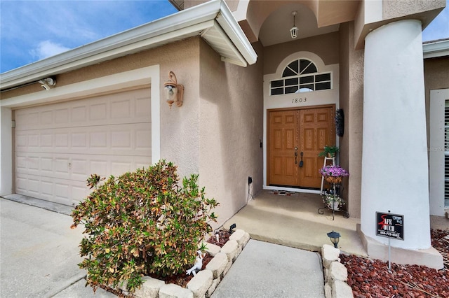 entrance to property with a garage and stucco siding