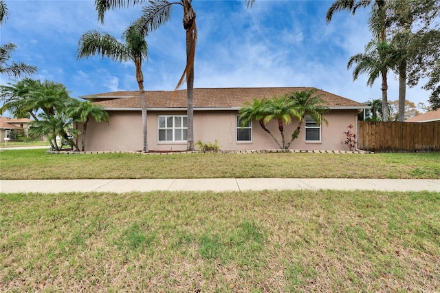 ranch-style home with a front yard, fence, and stucco siding