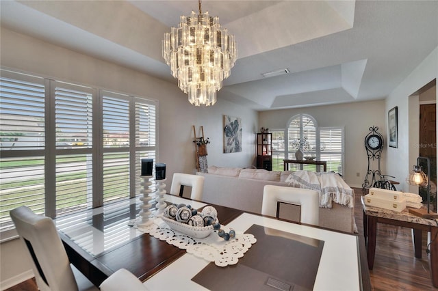 dining space with a chandelier, a raised ceiling, visible vents, and wood finished floors