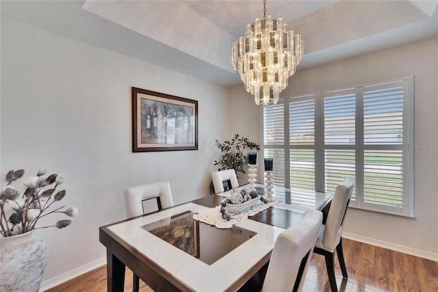 dining area featuring baseboards, wood finished floors, and a notable chandelier