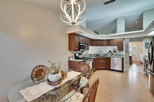 kitchen with baseboards, appliances with stainless steel finishes, an inviting chandelier, light wood-style floors, and a sink