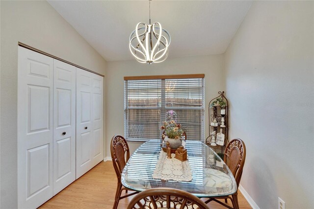 dining space featuring vaulted ceiling, light wood-type flooring, a chandelier, and baseboards