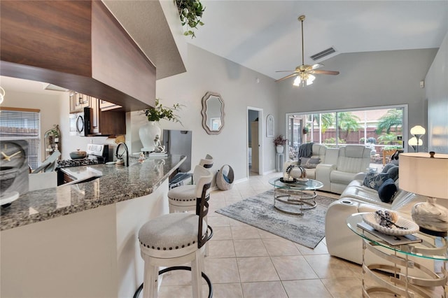 living room with light tile patterned floors, high vaulted ceiling, visible vents, baseboards, and a ceiling fan