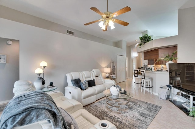 living room featuring light tile patterned floors, baseboards, visible vents, a ceiling fan, and vaulted ceiling