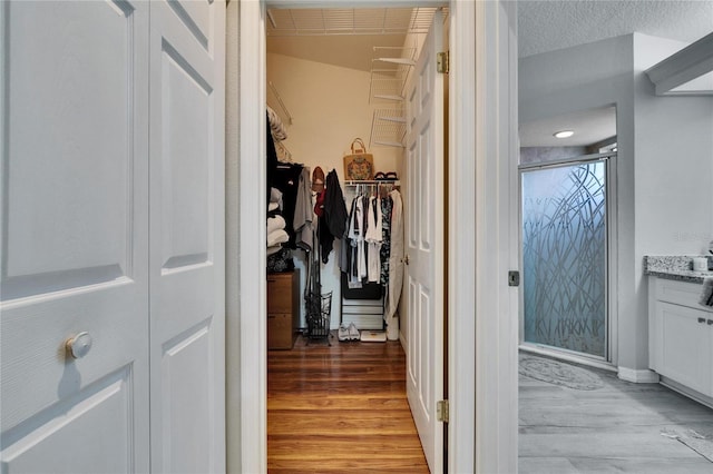 corridor with a textured ceiling and light wood finished floors