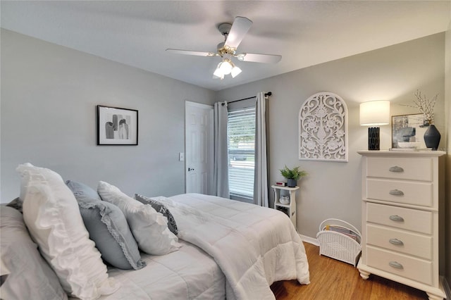 bedroom featuring wood finished floors, a ceiling fan, and baseboards