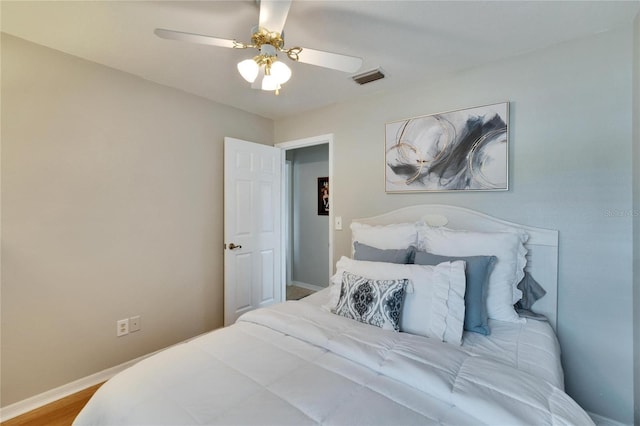 bedroom with a ceiling fan, wood finished floors, visible vents, and baseboards