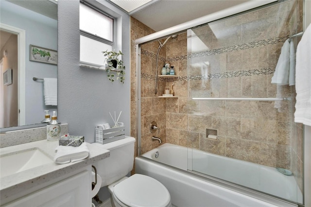 bathroom featuring toilet, combined bath / shower with glass door, and vanity