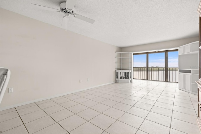 unfurnished living room featuring a textured ceiling, light tile patterned floors, a ceiling fan, and baseboards