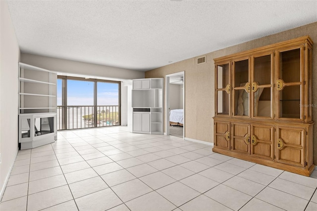 unfurnished living room with baseboards, visible vents, a textured ceiling, and light tile patterned flooring