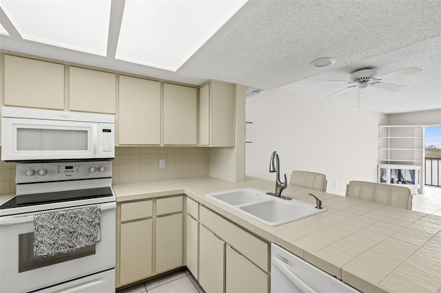 kitchen featuring a sink, white appliances, backsplash, and cream cabinetry