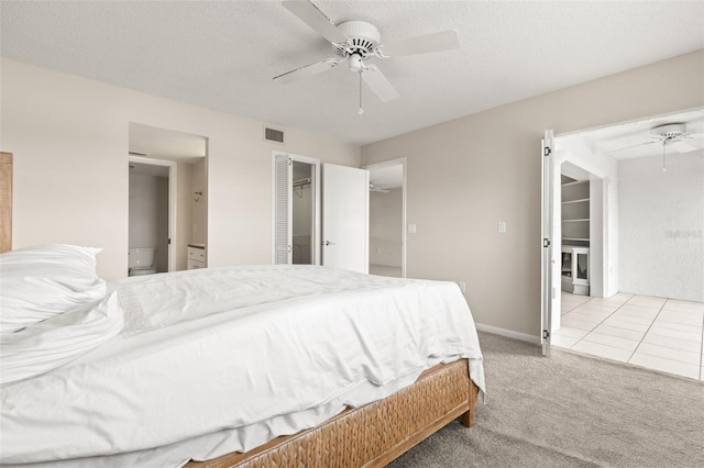 carpeted bedroom featuring a textured ceiling, tile patterned flooring, visible vents, and a ceiling fan