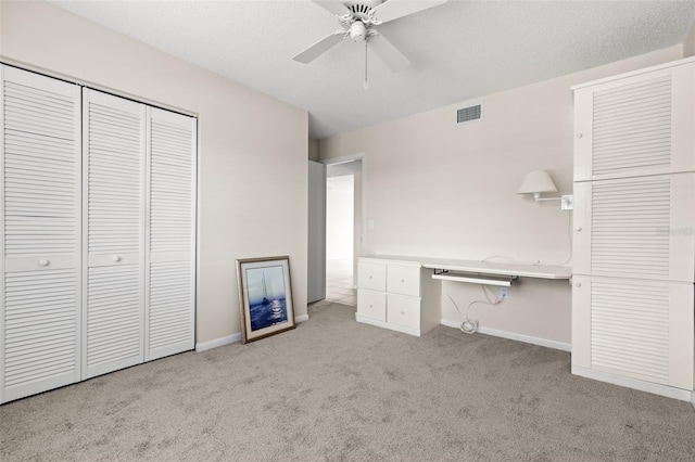 unfurnished bedroom featuring carpet floors, a closet, visible vents, a textured ceiling, and baseboards