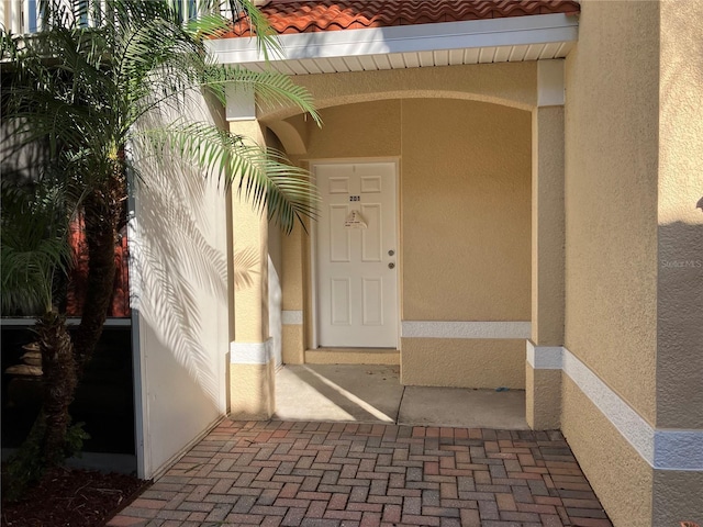 view of exterior entry with a tiled roof and stucco siding