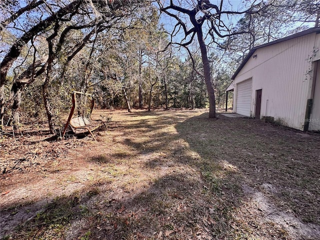 view of yard with a garage, driveway, and an outbuilding