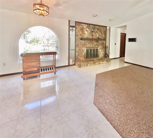 tiled living area with a fireplace, a textured ceiling, and baseboards