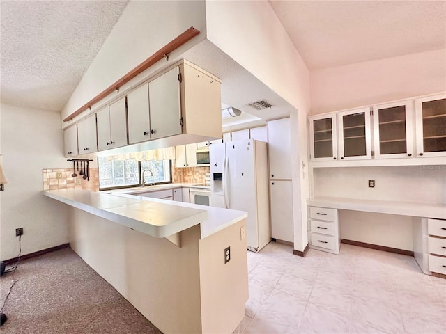 kitchen with white appliances, built in study area, a peninsula, light countertops, and backsplash