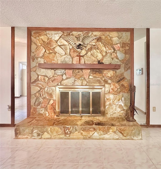 interior details featuring a textured ceiling, a stone fireplace, and baseboards