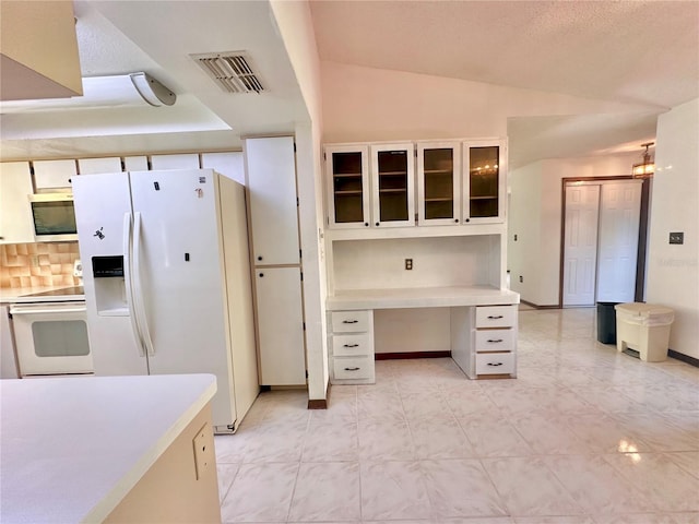 kitchen featuring white appliances, visible vents, vaulted ceiling, light countertops, and built in desk