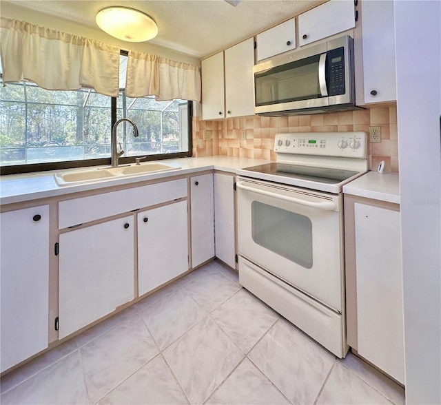 kitchen with white electric range, a sink, light countertops, backsplash, and stainless steel microwave