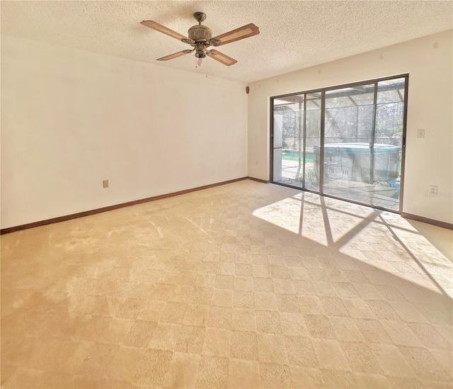 spare room with a textured ceiling, ceiling fan, and baseboards