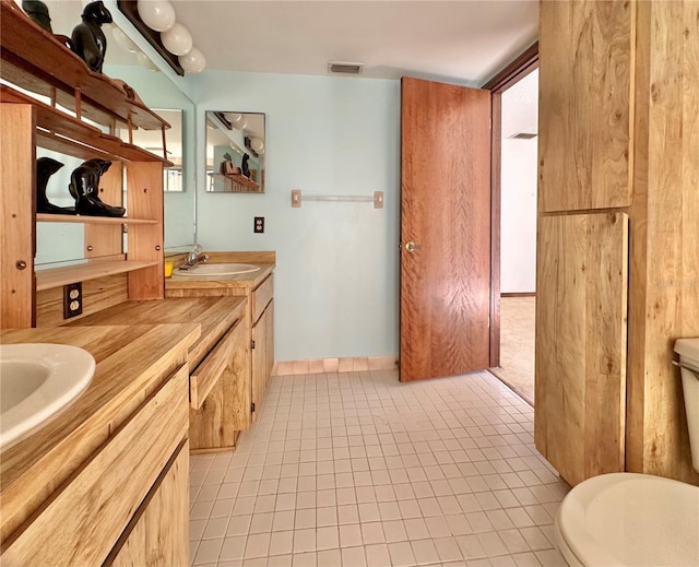 bathroom featuring visible vents, vanity, toilet, and tile patterned floors