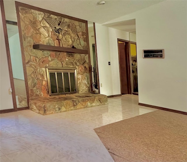 living room featuring a stone fireplace and baseboards