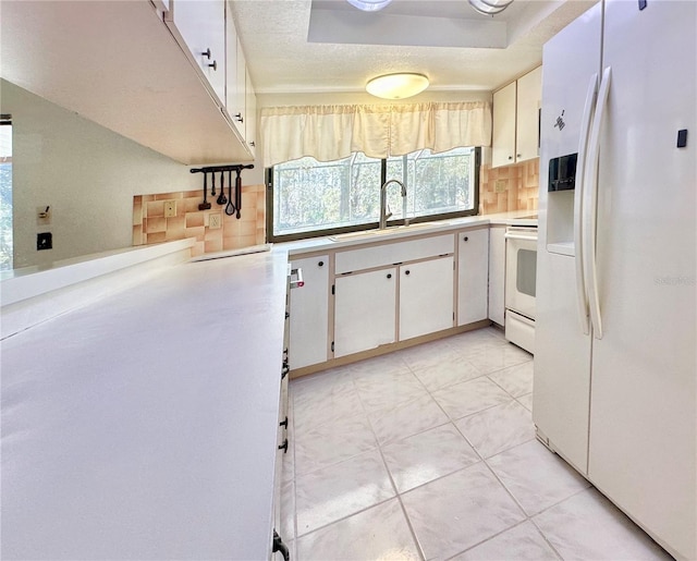 kitchen featuring white appliances, decorative backsplash, light countertops, white cabinetry, and a sink