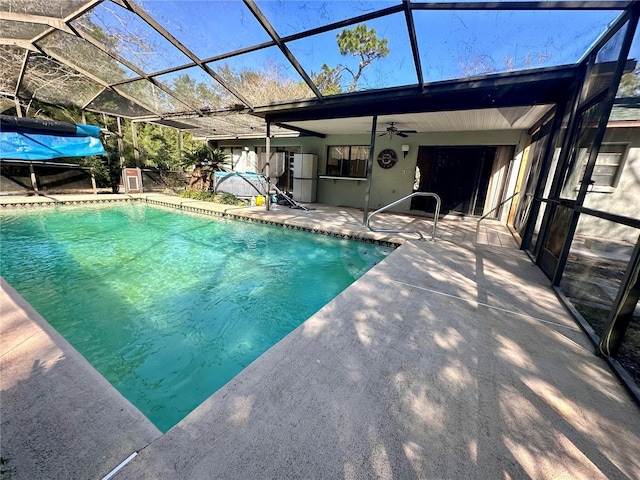 pool featuring glass enclosure, a patio area, and a ceiling fan