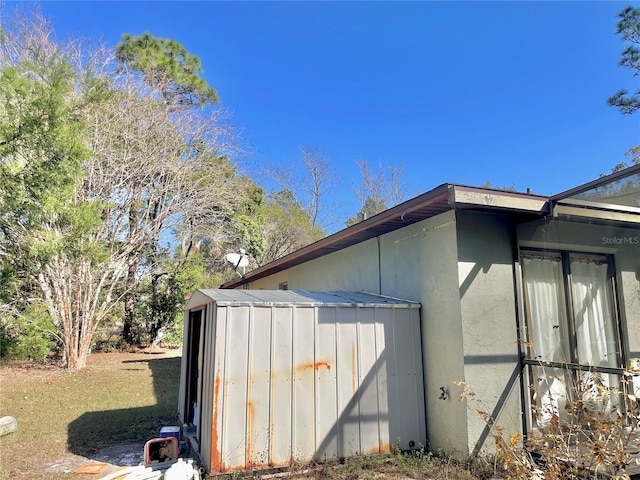 view of side of home with stucco siding, a shed, and an outbuilding