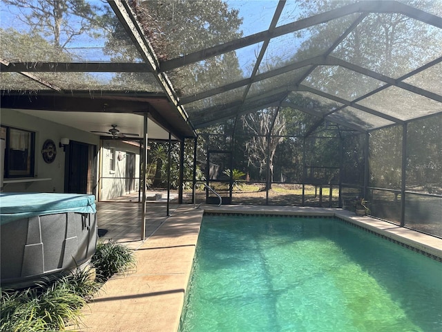 pool featuring glass enclosure, a patio area, and ceiling fan