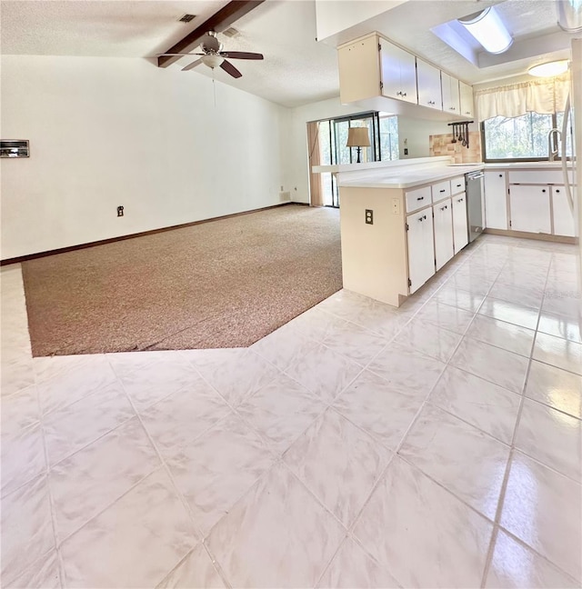 kitchen featuring light colored carpet, lofted ceiling with beams, dishwasher, a peninsula, and baseboards