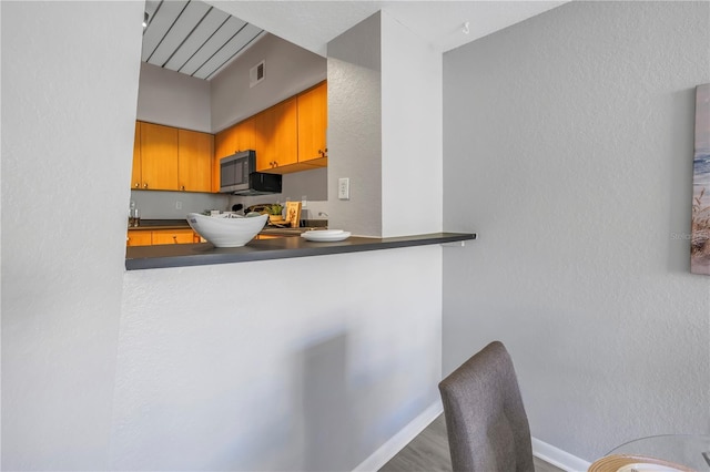 2402 W Azeele St Unit 423, Tampa, FL 33609 - kitchen featuring stainless steel microwave, dark countertops, and wood finished floors
