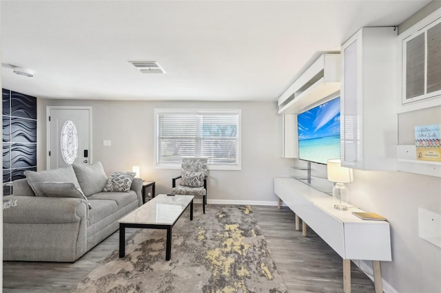 living room featuring wood finished floors, visible vents, and baseboards